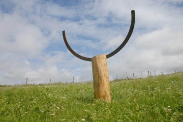 Wood and metal sculpture in field.